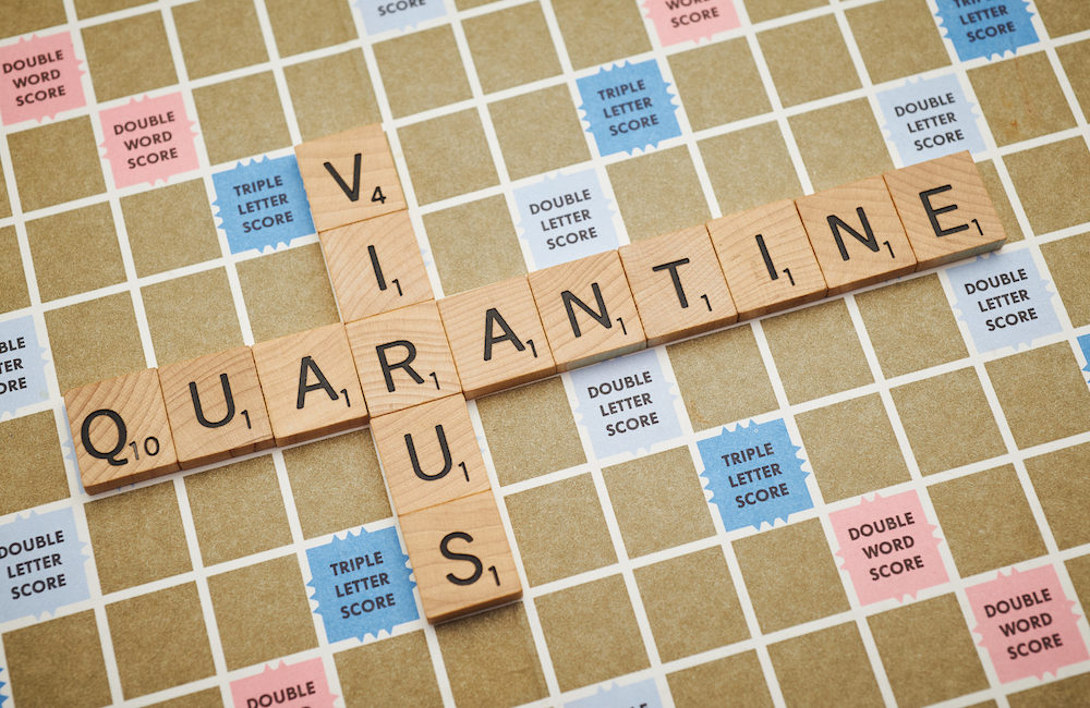 scrabble board with virus and quarantine spelled out