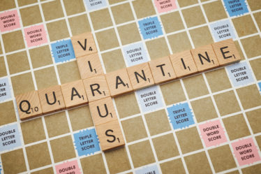 scrabble board with virus and quarantine spelled out